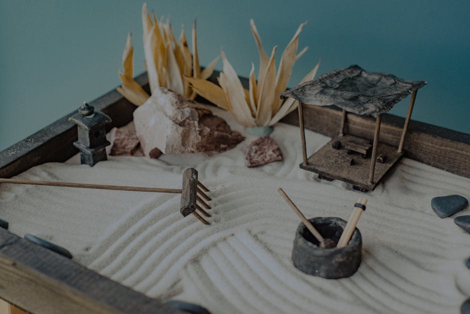 A calming miniature Zen garden featuring sand, stones, and decorative elements like a pavilion and lantern.